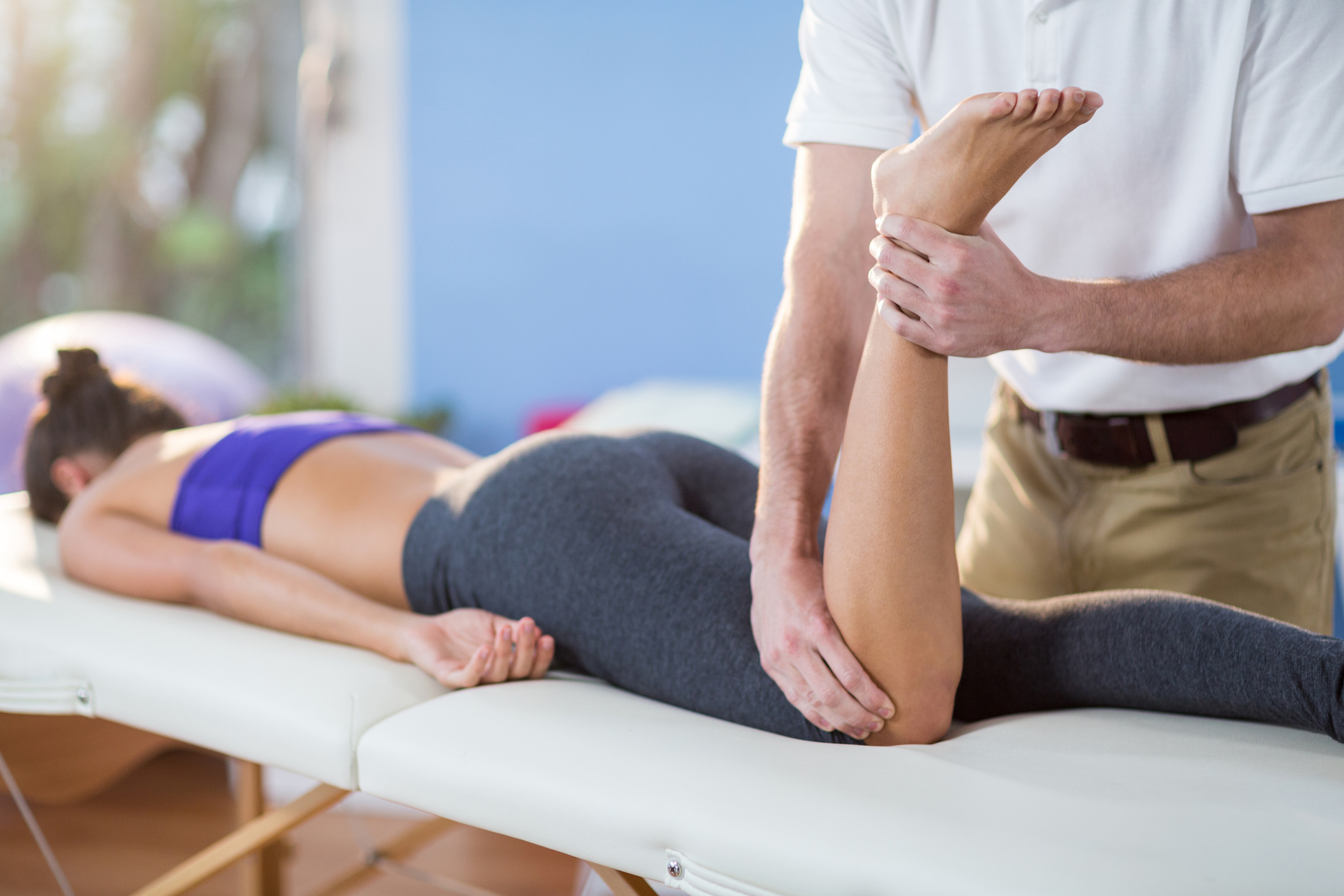 Male physiotherapist giving knee massage to female patient