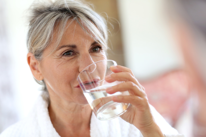 Woman in bathrobe drinking water