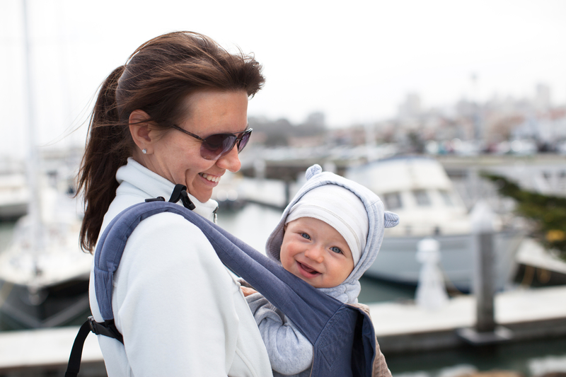 Mother and a smiling cute baby boy in a baby carrier
