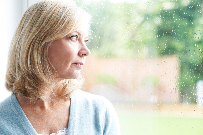 Sad Mature Woman Suffering From Agoraphobia Looking Out Of Windo